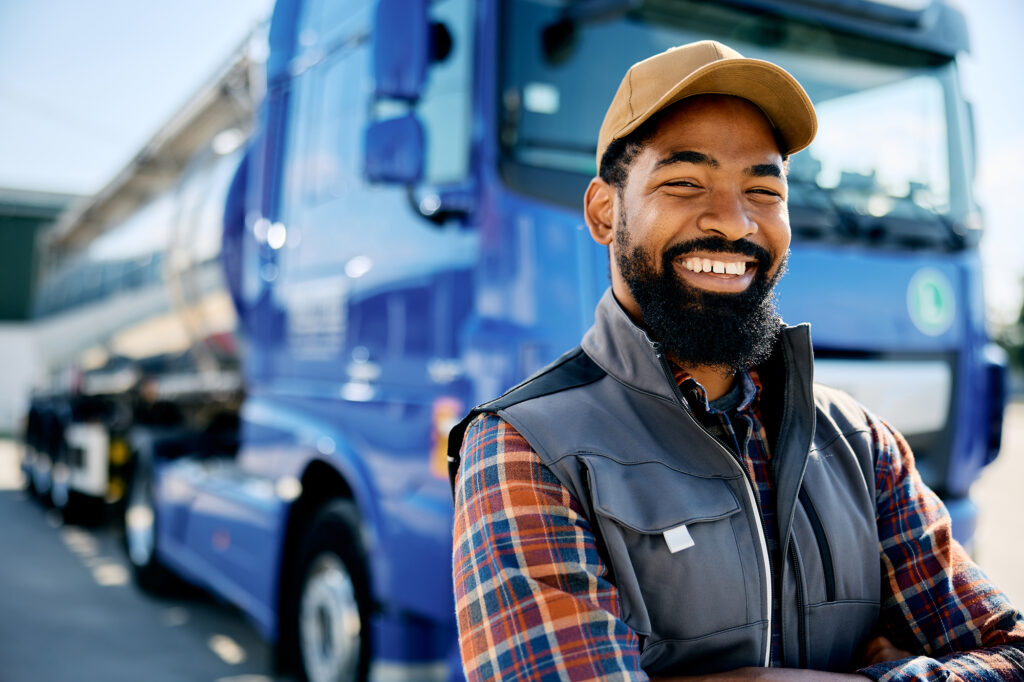 A truck driver smiling in front of a semi truck. Superior Truck Driving Academy Oklahoma CDL Commercial Driver License and Permit