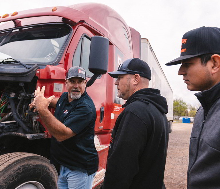 An instructor at Superior Truck Driving Academy gives a hands-on lesson to students